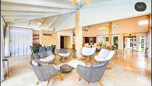 A spacious living room with wicker furniture, a ceiling fan, and a view of the dining area. - Snrvittinivillas Mng Spacius and Best Loc in Casa de Campo Resorts Gr8 Villa (La Romana)