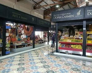 Ein Markt mit Ständen, auf denen 'ARTESANIAS ARTE A MANO' und 'FRUTAS Y VERDURAS DONA CARMEN' steht.