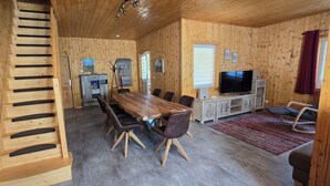 Ein Holzinterieur mit Esstisch, Stühlen, einem Fernseher und einem Kamin.