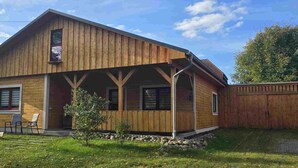 Ein Holzhaus mit Veranda, kleinem Garten und Zaun.