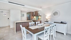Una cocina moderna con una isla central, sillas blancas y una mesa de comedor.