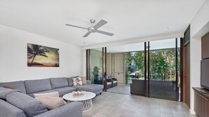 Una sala de estar moderna con un sofá gris, una mesita de centro redonda y un ventilador de techo.
