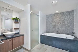 Un baño moderno con una bañera independiente, un espejo grande y un lavamanos con encimera de mármol.