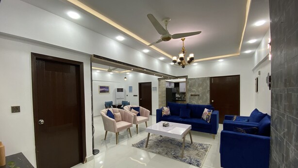 Un salon moderne avec un ventilateur de plafond, un lustre et un canapé bleu.