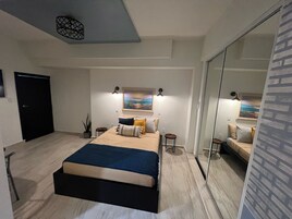 Un dormitorio moderno con una cama grande, una mesita de noche, un espejo y una puerta.