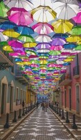 Un pasillo decorado con paraguas de colores suspendidos del techo, creando un ambiente vibrante.