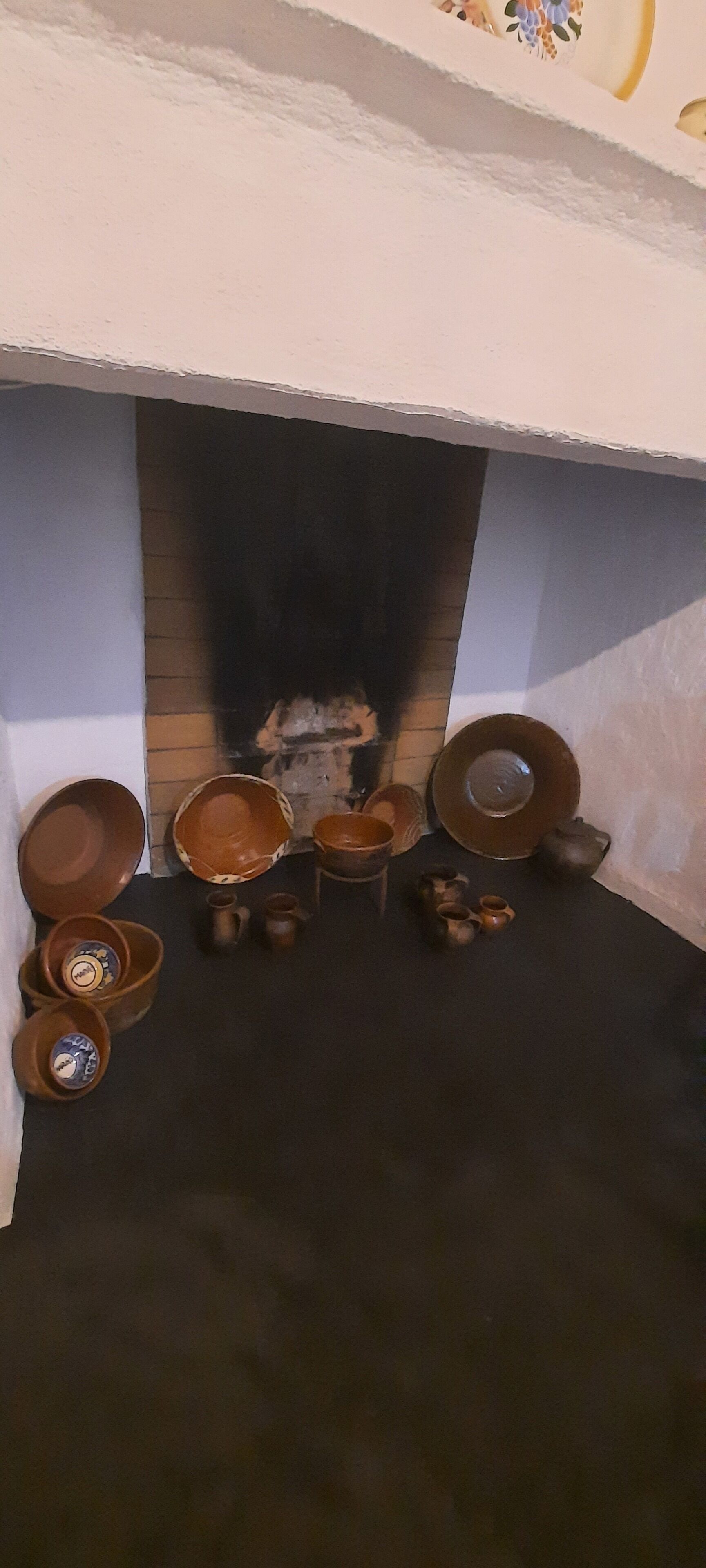 Une cheminée agrémentée de divers objets en céramique disposés autour.