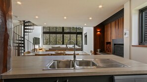 Cozinha moderna com ilha central, fogão embutido e uma ampla janela com vista para um deck.