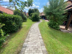 A paved pathway leading through a well-maintained garden with various shrubs and trees.