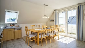 Et køkken med spisebord, stole, et vindue og udsigt ud