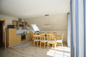 Une cuisine compacte dotée de meubles en bois, d’un four à micro-ondes et d’un coin repas avec une table et des chaises.