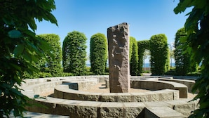 En stenhøj omgivet af en cirkelformet stiensløjfe i en park.