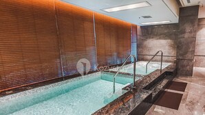 A swimming pool with a wooden wall and a marble floor. - EBONY by Kozystay (Jakarta)