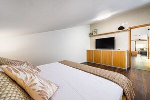 A hotel room with a bed, a television, wooden cabinets, and a mirror. - Sunset Suite Premium Apartment (Porec)