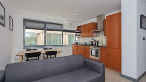 Une cuisine moderne avec des meubles en bois, un four encastré et une fenêtre donnant sur la ville.