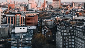 Une vue urbaine avec un gratte-ciel imposant au centre, entouré de différents bâtiments et traversé par une rivière.