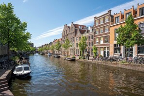 A canal lined with traditional buildings, a boat docked on the left, and bicycles parked along the right. - Pakasa Leiden (Leiden)