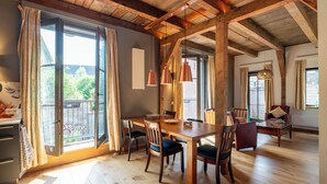 A spacious room with a wooden dining table, chairs, and a large window with curtains. - Pakasa Leiden (Leiden)