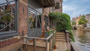 A canal-side building with a wooden staircase leading to a balcony, a brick facade, and a view of the canal. - Pakasa Leiden (Leiden)