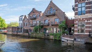 A canal-side building with multiple balconies and a boat docked nearby. - Pakasa Leiden (Leiden)