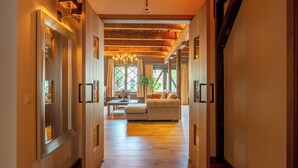 A hallway with wooden floors and walls, leading to a living area with a sofa and a chandelier. - Pakasa Leiden (Leiden)