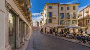 A cobblestone street lined with buildings, outdoor seating at cafes, and a distant castle. - SUITE ARENA IN CENTRO CITTA' (Verona)