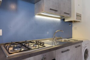 A modern kitchen with a gas stove, stainless steel sink, and built-in oven.