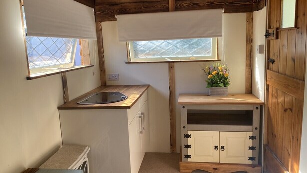 Una cocina compacta con un lavamanos, una ventana y un pequeño mueble con una planta.