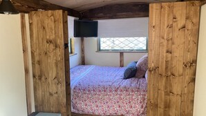 Un dormitorio con una cama, televisión y ventana.
