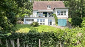Ein zweistöckiges Haus mit einem Ziegeldach, einem Balkon und einem umzäunten Garten.