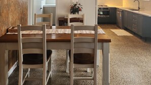 Una cocina moderna con zona de comedor, que presenta una mesa de madera con sillas, una lámpara colgante y una encimera de cocina con armarios.