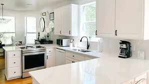 A modern kitchen with white cabinetry, stainless steel appliances, and a large island. - Turquoise Tides- Dog Friendly! Heated Pool- 6 Bike (Santa Rosa Beach)