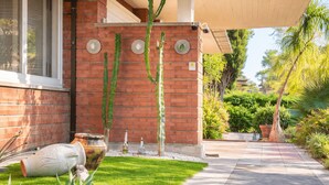 Un edificio de ladrillo con un jardín de cactus, un camino y un patio cubierto.