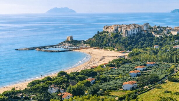 Un pueblo costero con una playa, un castillo y edificios residenciales.