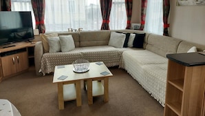 A cozy living room with a sofa, TV, and a table. - Cozy Coastal Retreat in Brean (Burnham-on-Sea)