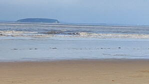 A beach with waves and a distant landform. - Cozy Coastal Retreat in Brean (Burnham-on-Sea)