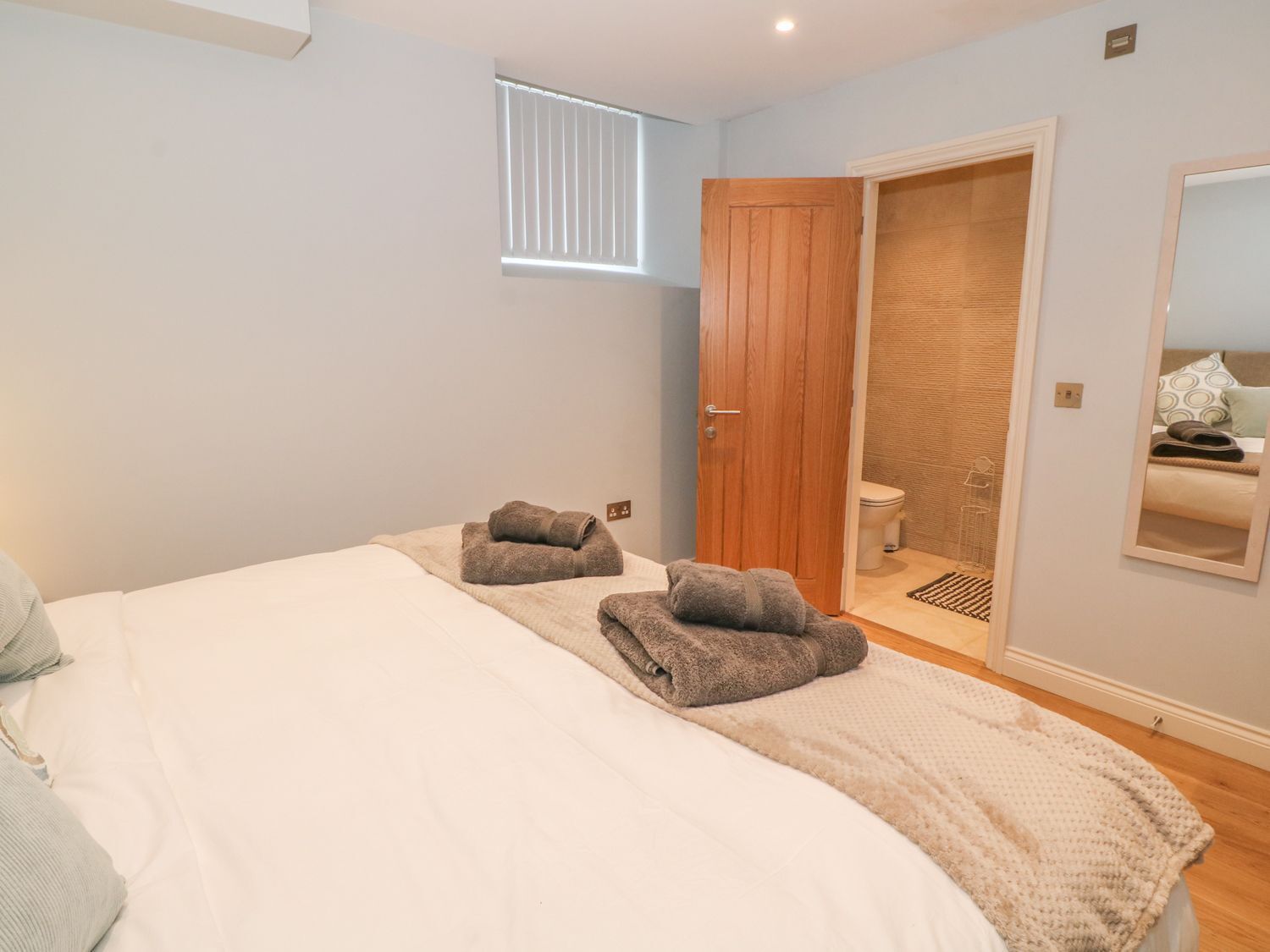 A bedroom with a large bed, two towels, a wooden door, and a mirror.