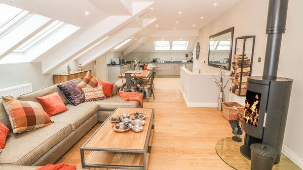 A modern loft apartment with a high ceiling, skylights, a central fireplace, and a cozy seating area. - Sardis Chapel 1 (Bodorgan)