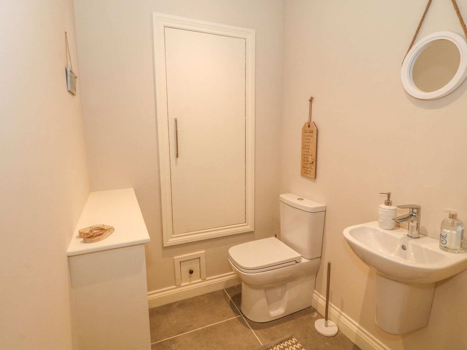 A bathroom with a toilet, sink, and a mirror on the wall.