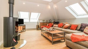A modern loft apartment with a high ceiling, skylights, a fireplace, a sofa, and a coffee table. - Sardis Chapel 1 (Bodorgan)