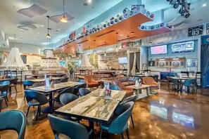 A restaurant with multiple dining areas, including a bar area with a counter and stools. Tables and chairs are arranged in a spacious layout.