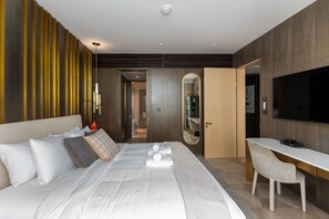 Une chambre d’hôtel moderne équipée d’un grand lit, d’un bureau, d’une chaise, d’une télévision et d’un miroir.