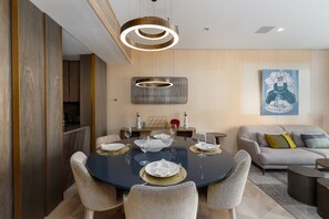 A modern dining area with a round table, chairs, and a contemporary light fixture.