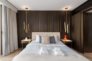 Moderni hotellihuone, jossa on suuri sänky, kaksi yöpöytää ja pieni sivupöytä.