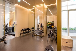 Ein Fitnessstudio mit Trainingsgeräten, Laufband und Spiegel.