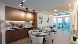 A modern kitchen with wooden cabinets, a marble backsplash, and a dining area with a round table and chairs.