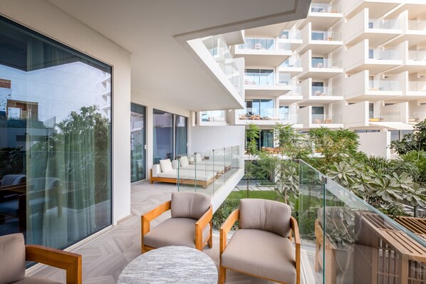 A modern hotel with a spacious balcony, large windows, and a view of the surrounding greenery.