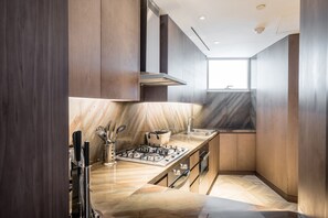 A modern kitchen with dark wood cabinets, a marble countertop, and stainless steel appliances.