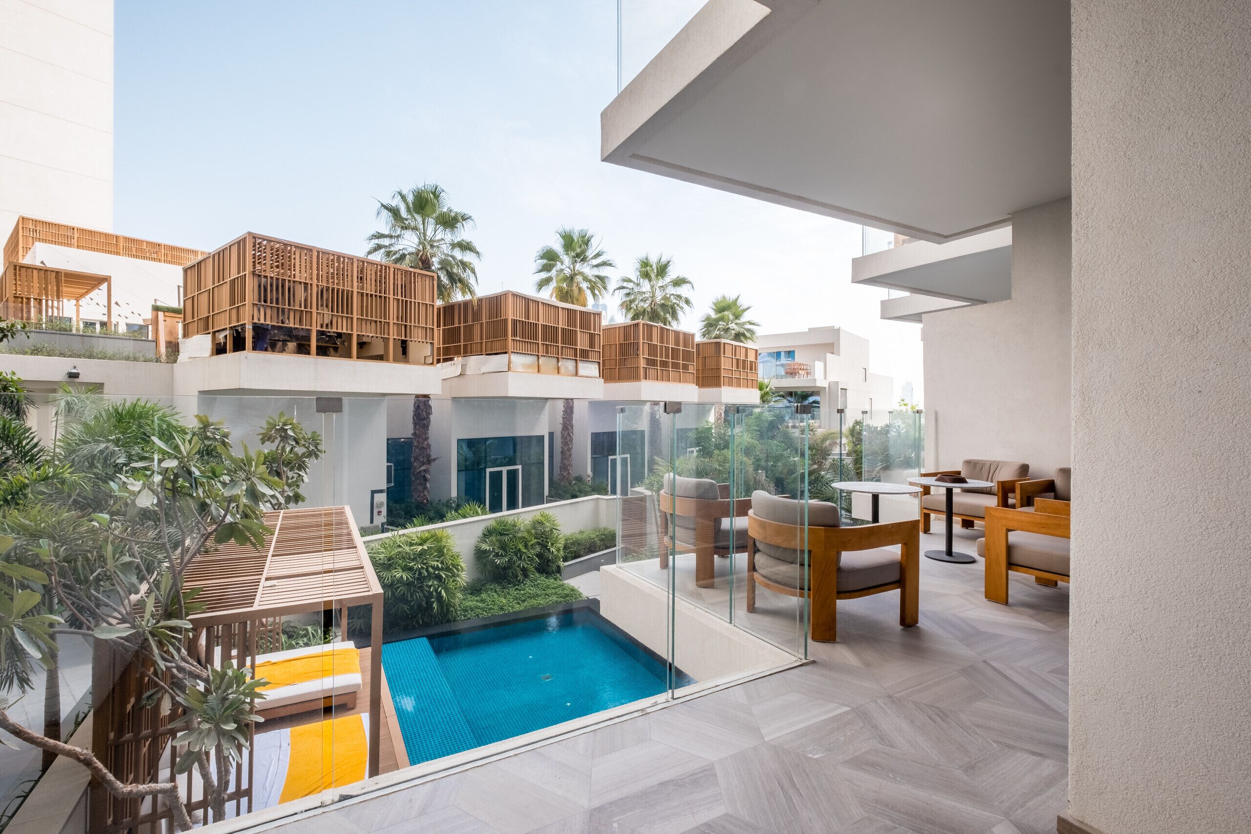 Een modern hotel met een dakterraszwembad, buiten zitplaatsen en weelderige beplanting.