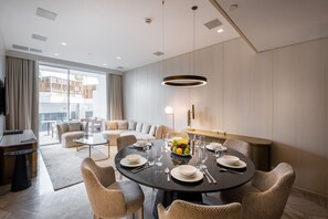 A modern dining area with a round table set for six, surrounded by wicker chairs.